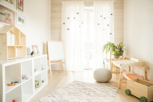 Spacious children's room in a modern style with Montessori furniture, including white toy shelves and a wooden drawing table